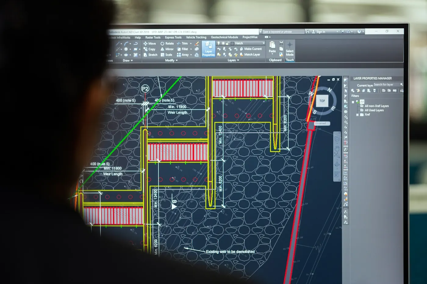 An engineer working on a CAD layout drawing on a large monitor