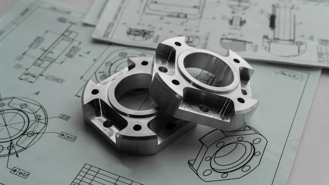 Machined parts resting on engineering drawings